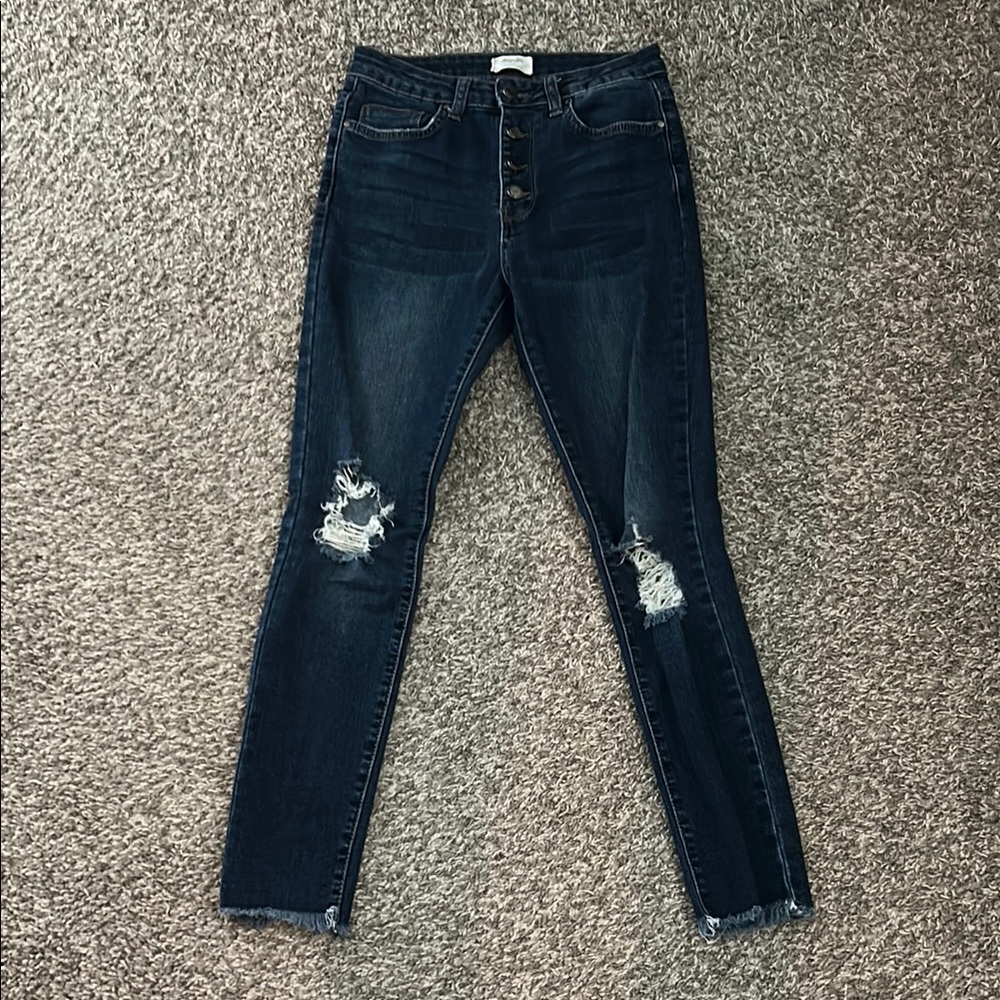 Dark distressed button closure skinny jeans with frayed detail at the ankle